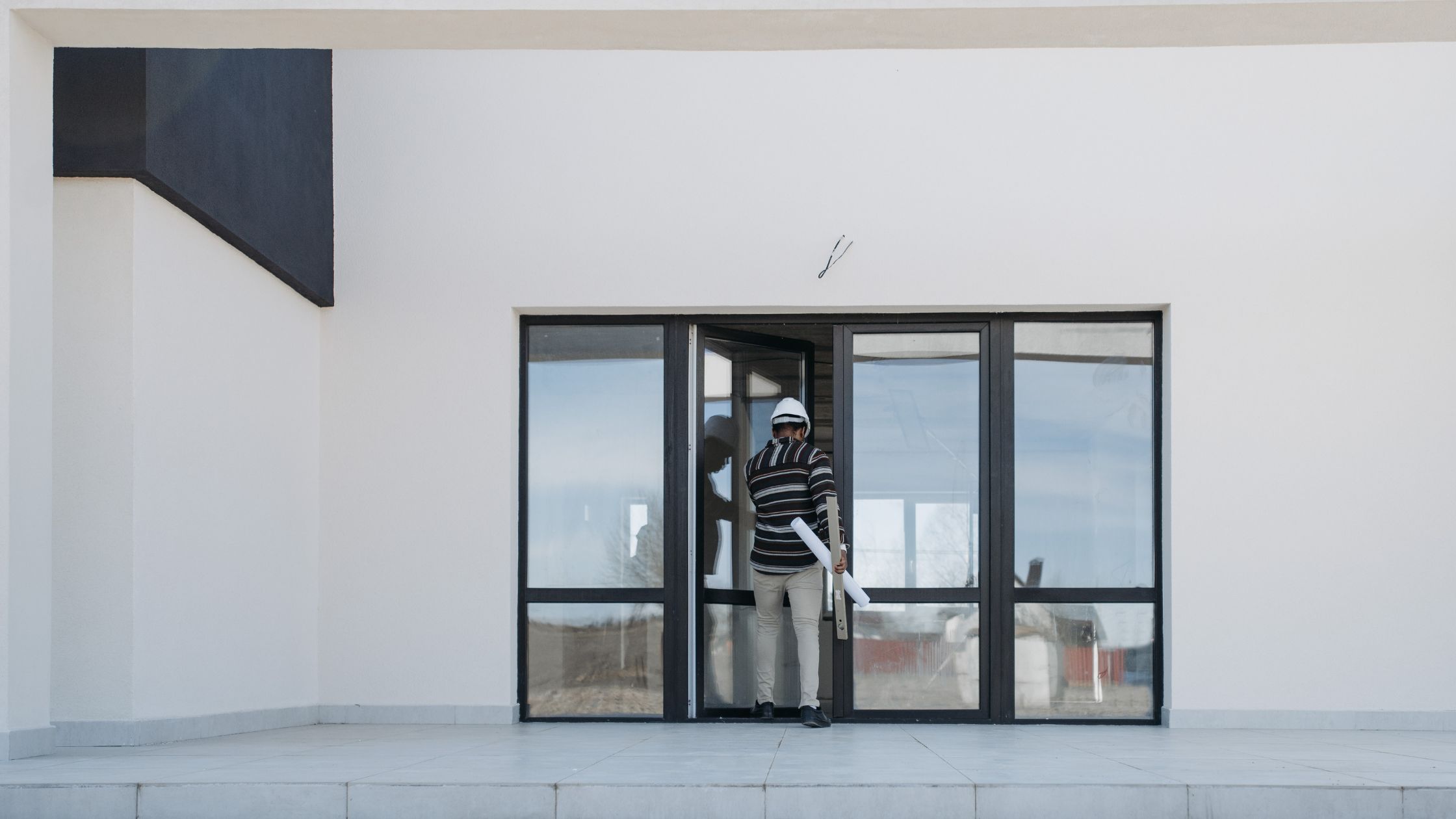 puerta con ventanales donde el constructor está entrando dentro de la vivienda